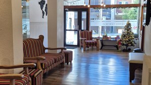 A spacious lobby with wooden flooring, striped armchairs, and a Christmas tree. - Hotel Nordico (San Carlos de Bariloche)