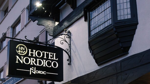 A hotel sign with "HOTEL NORDICO" and a logo. - Hotel Nordico (San Carlos de Bariloche)