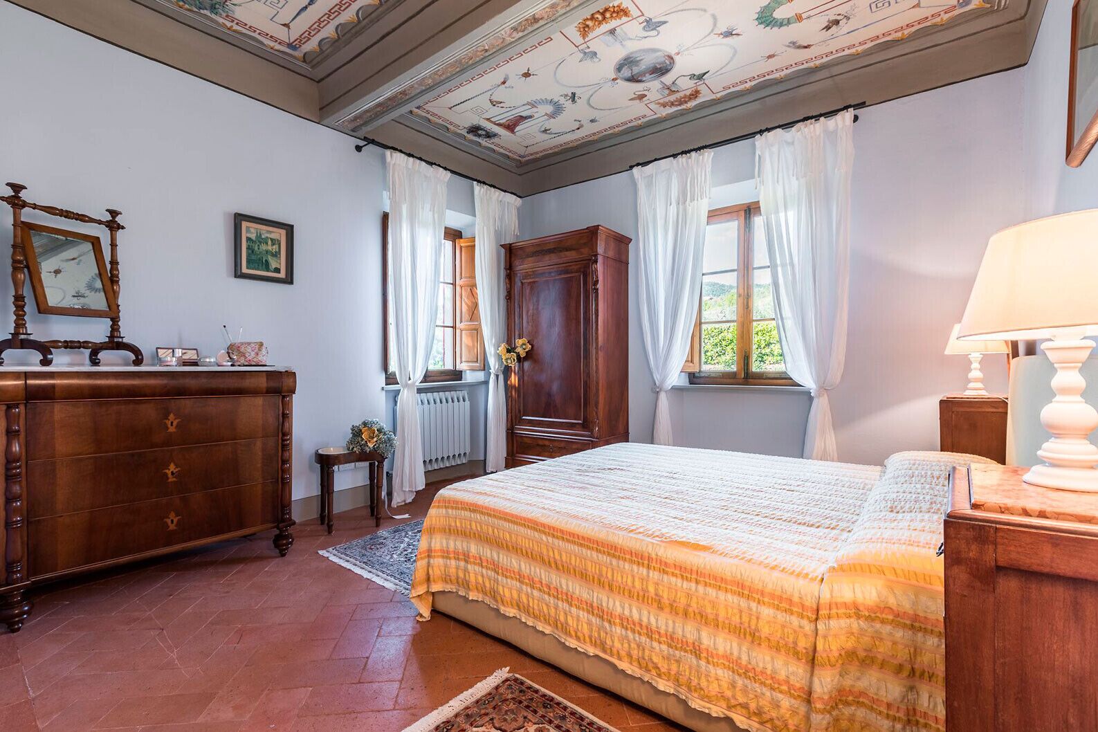 Una camera da letto con un letto grande, una cassettiera in legno e un soffitto decorato con un affresco.