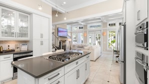 Une cuisine moderne avec des meubles blancs, un îlot central doté d’une plaque de cuisson et des appareils électroménagers intégrés.