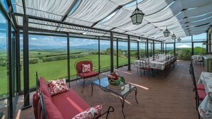 A covered outdoor dining area with a view of the countryside.