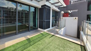 Un edificio moderno con amplios ventanales de vidrio, un patio con césped y una estructura metálica.