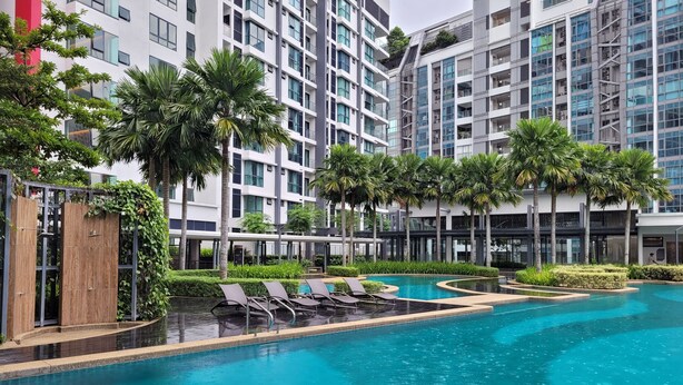 Un hotel moderno con piscina, palmeras y un jardín bien cuidado.