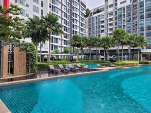 Un hotel moderno con piscina, palmeras y un jardín bien cuidado.