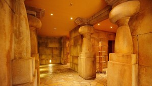 Un pasillo con columnas de piedra y suelo de mosaico.