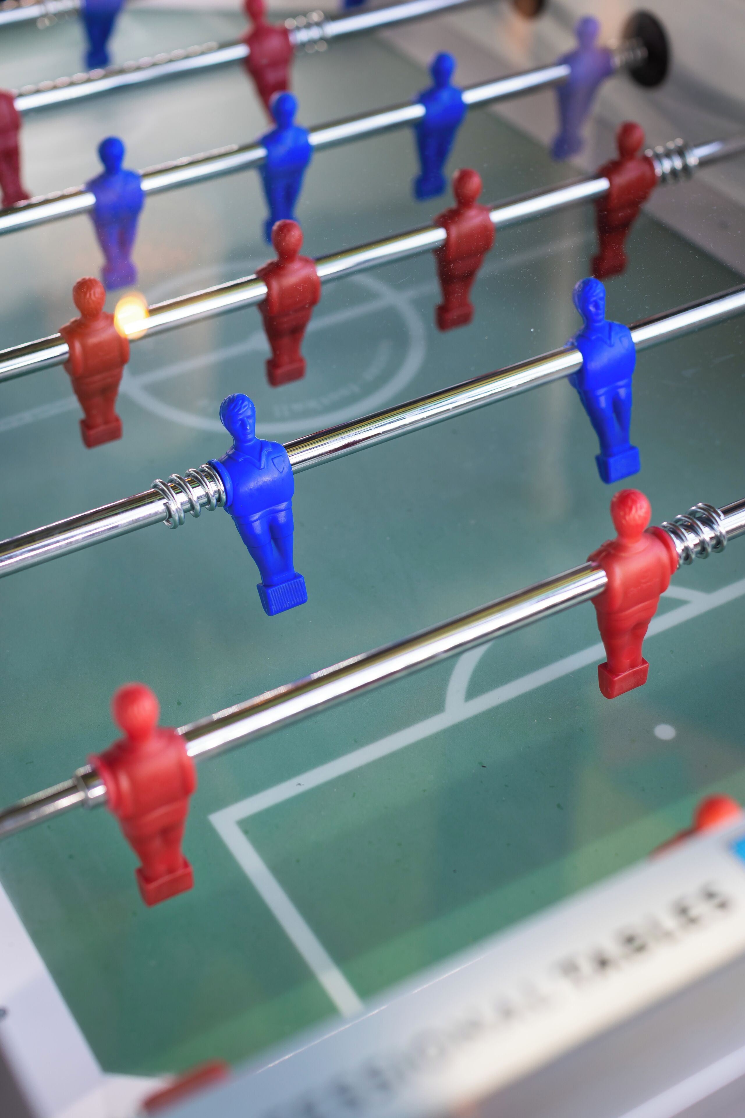 Ein Detailbild eines Kicker-Tisches mit roten und blauen Spielfiguren.