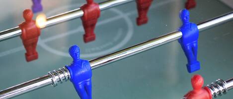 Ein Detailbild eines Kicker-Tisches mit roten und blauen Spielfiguren.