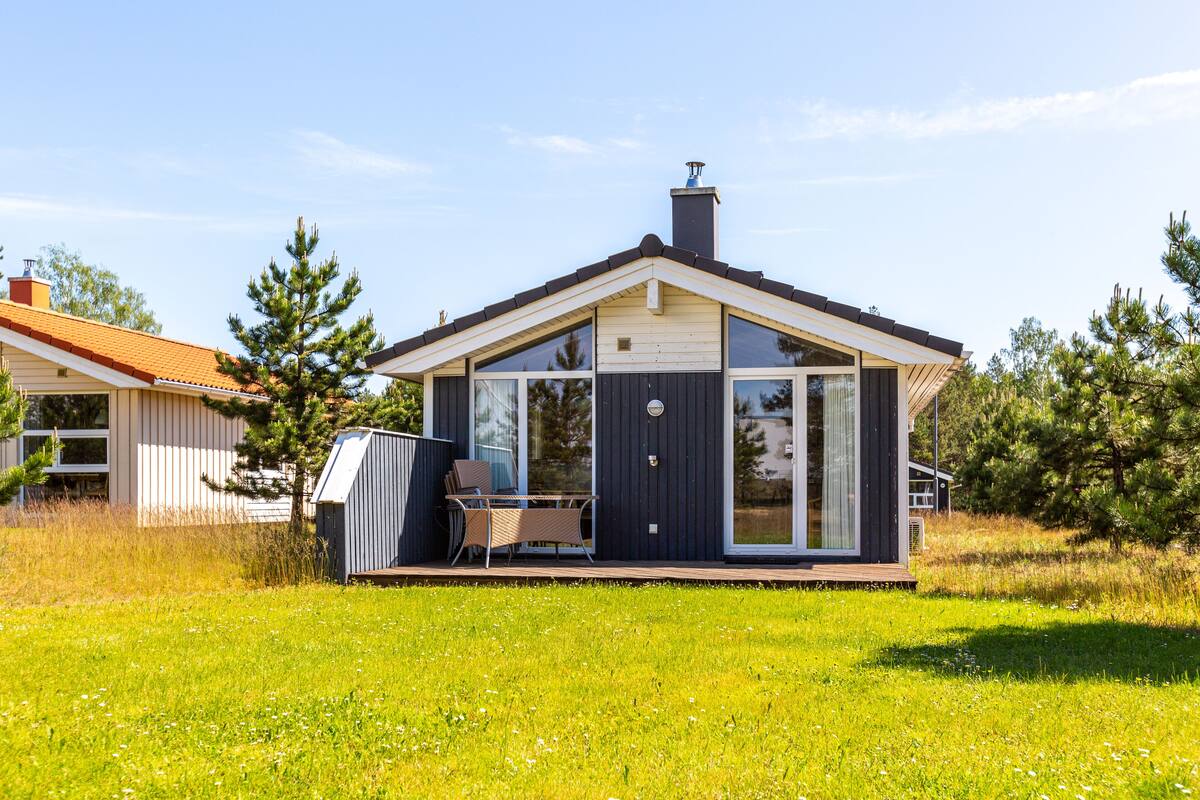 Una casa moderna con una terraza amplia, una chimenea y un césped bien cuidado.