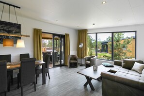 A modern living room with a dining area, large windows, and a view of the outdoors. - Tropical Islands Resort (Krausnick-Gross Wasserburg)