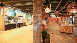 Interior de un restaurante con mostrador, empleados y una pizarra de menú.