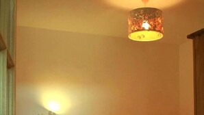 Habitación con literas, cabecero de madera, mesita de noche pequeña y lámpara de pared.