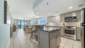 A modern kitchen with a large island, stainless steel appliances, and a dining area with a view. - INCREDIABLE WEST END CAP VIEW, NICE PROPERTY, GREAT FOR FAMILIES! (Orange Beach)