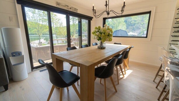 Un comedor con mesa de madera, sillas negras y un jarrón de flores.