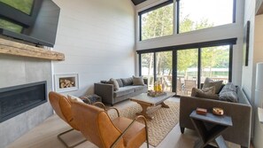 Una sala moderna con chimenea, sofás y un ventanal con vistas a una terraza.