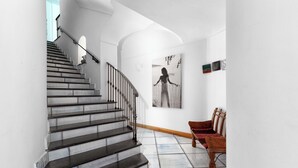 A staircase with black steps and white walls, leading to a landing with a bench and a framed picture. - Villa Le Sirene with Private Jacuzzi, Sea View (Positano)
