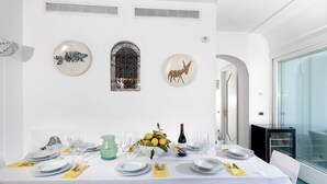A dining area with a white table set for a meal, decorated with a vase of lemons and a bottle of wine. - Villa Le Sirene with Private Jacuzzi, Sea View (Positano)