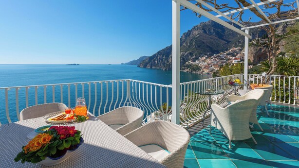A terrace with wicker furniture, a table with a fruit plate and drinks, and a view of the sea and mountains. - Villa Le Sirene with Private Jacuzzi, Sea View (Positano)