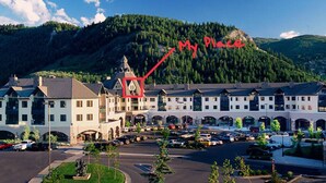Ein Hotel mit Hauptgebäude, Parkplatz und Bergkulisse.