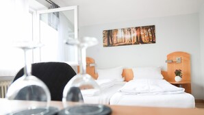 A hotel room with a bed, bedside tables, a painting, and a window. - Hotel & Gasthof Wagner (Aichach)