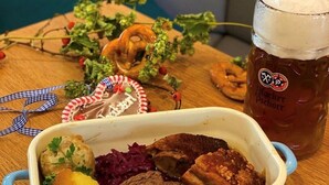 A meal with various dishes and a beer mug on a wooden table. - Hotel & Gasthof Wagner (Aichach)