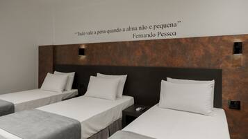 Two single beds with white linens and grey headboards, set against a dark brown textured wall.