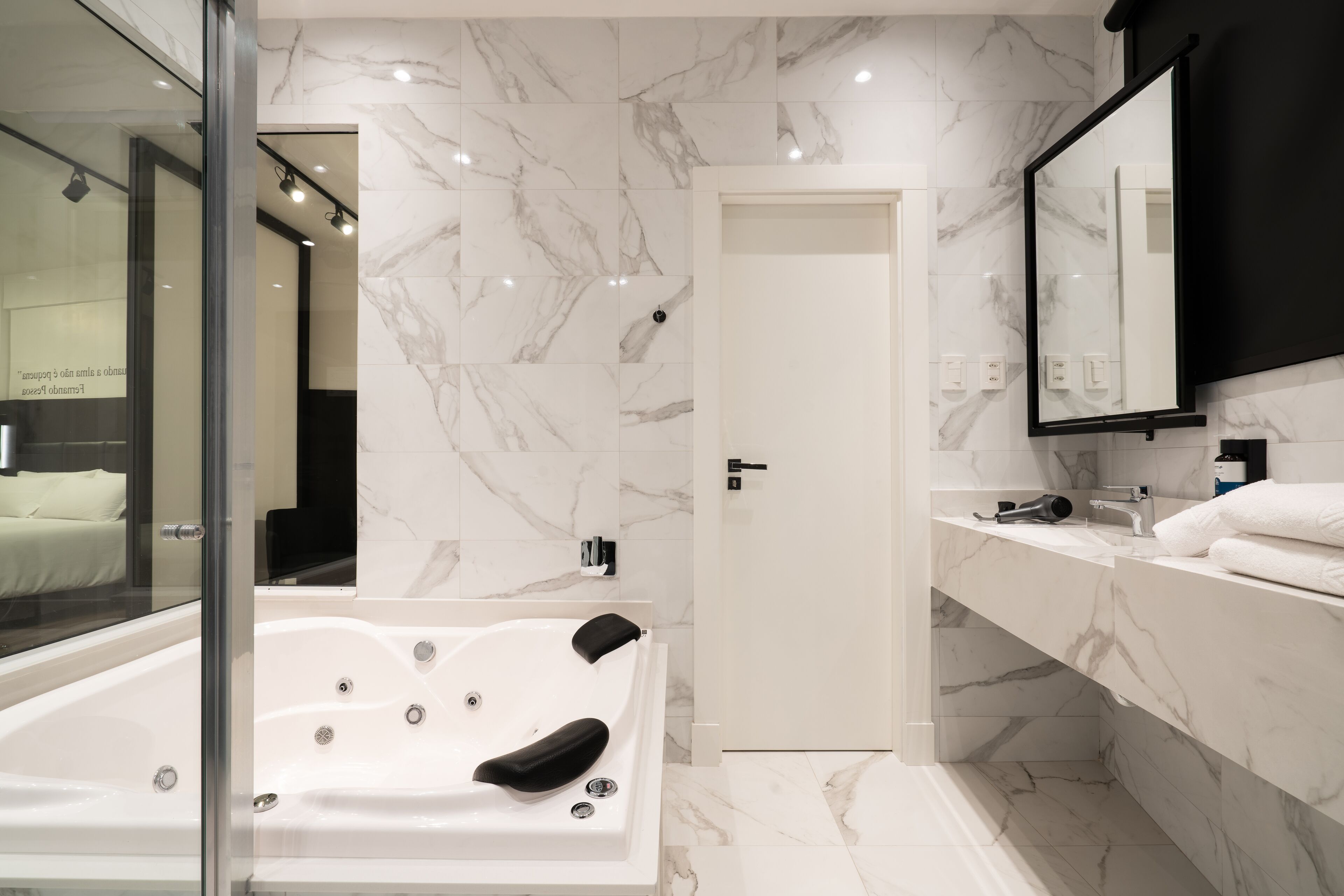 Un bagno moderno con pavimento in marmo, una vasca da bagno ampia, un box doccia in vetro e un mobile lavabo con specchio.