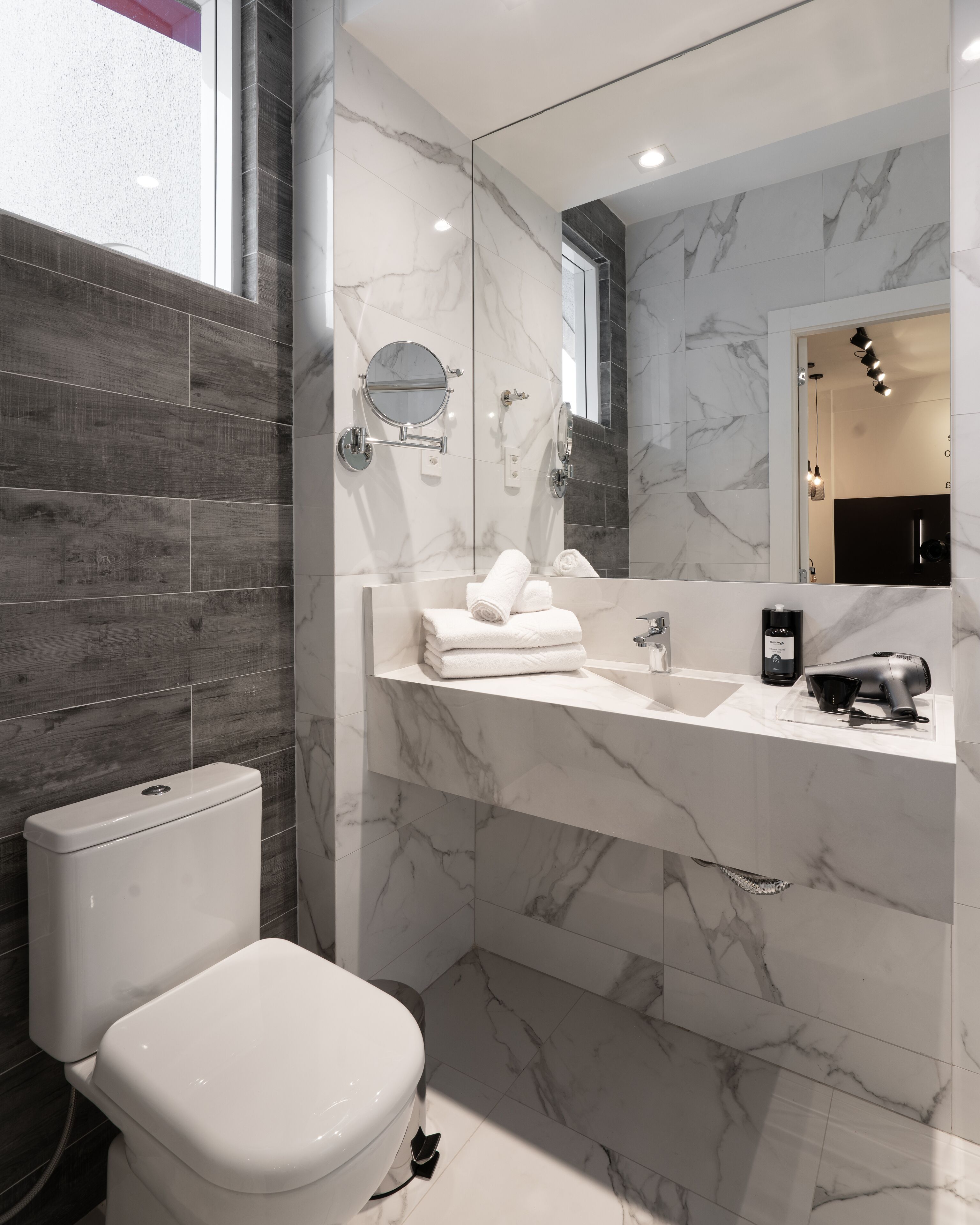 A modern bathroom with a marble sink, a toilet, and a mirror.
