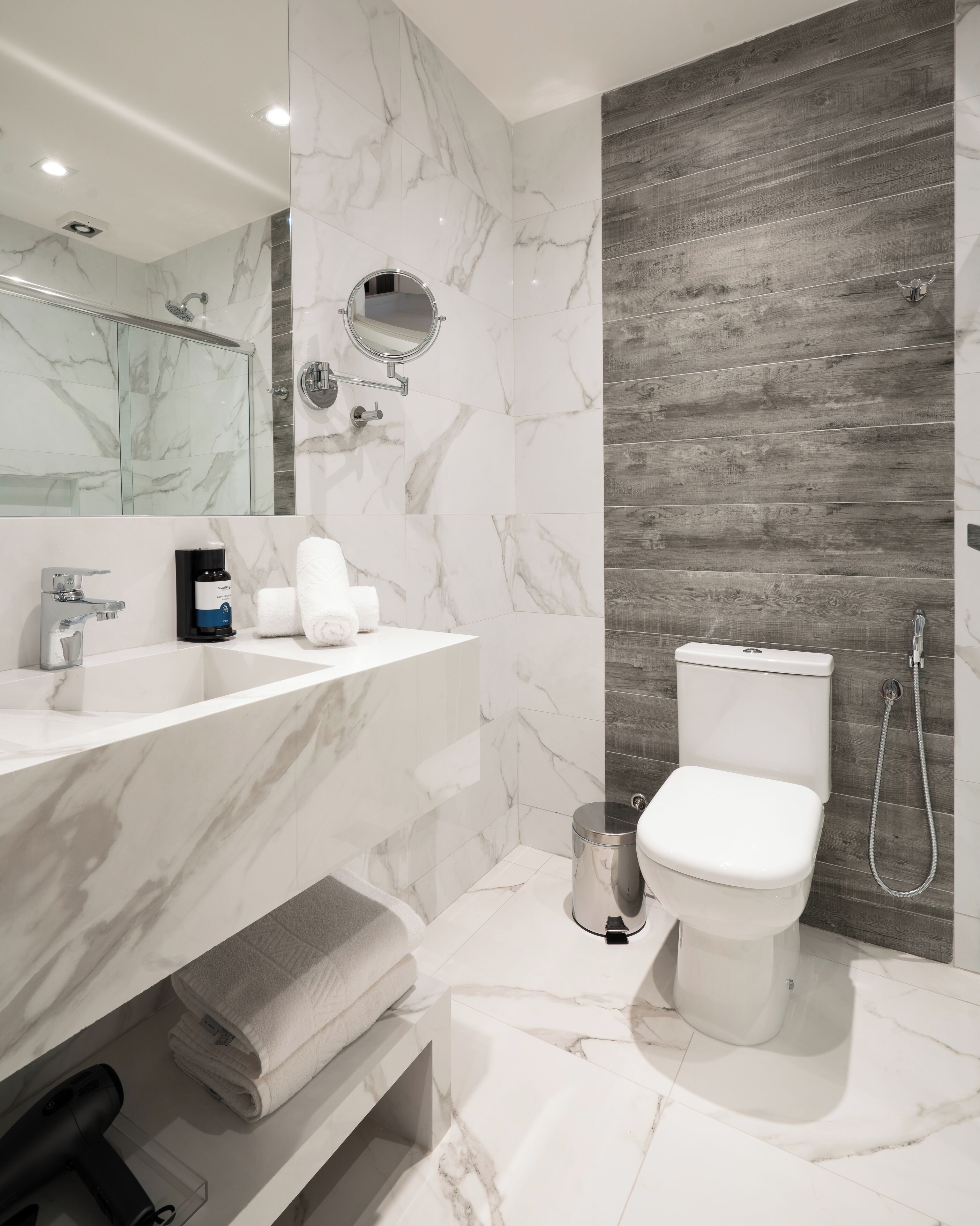 Un baño moderno con tocador de mármol, inodoro y ducha.