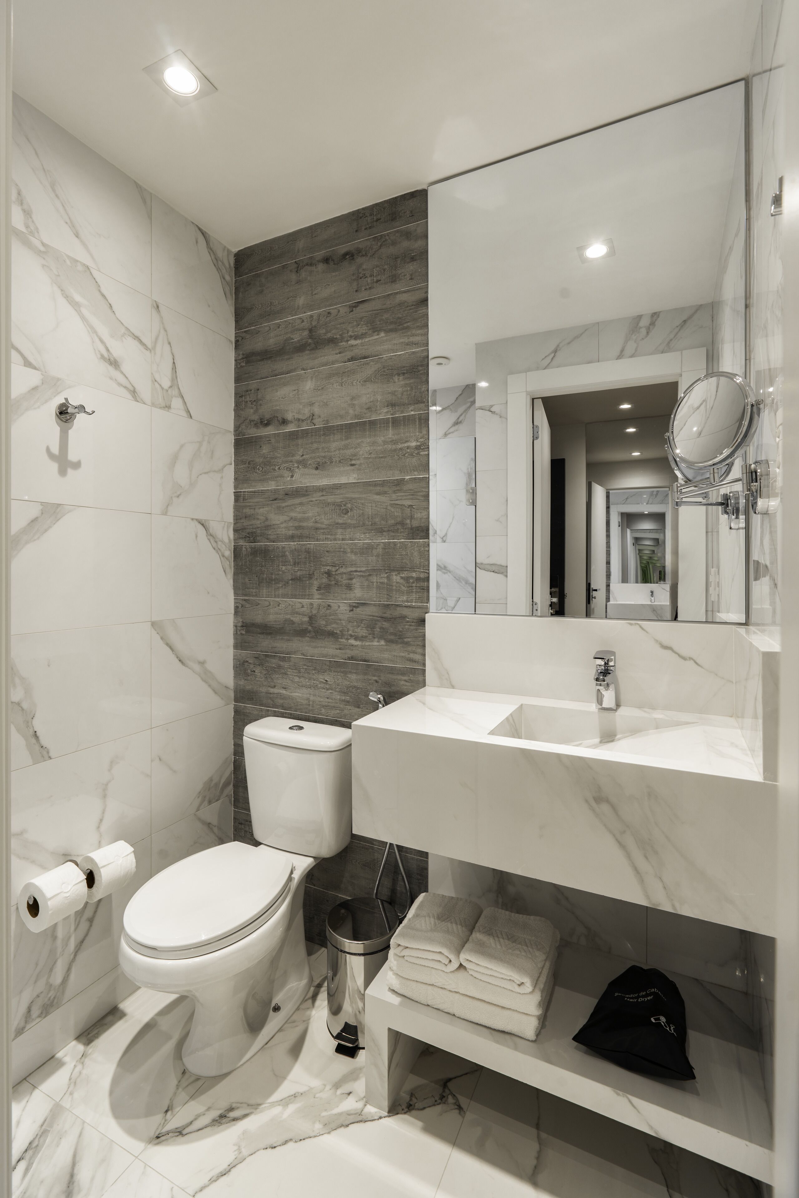Een moderne badkamer met een marmeren wastafel, toilet en wastafel.