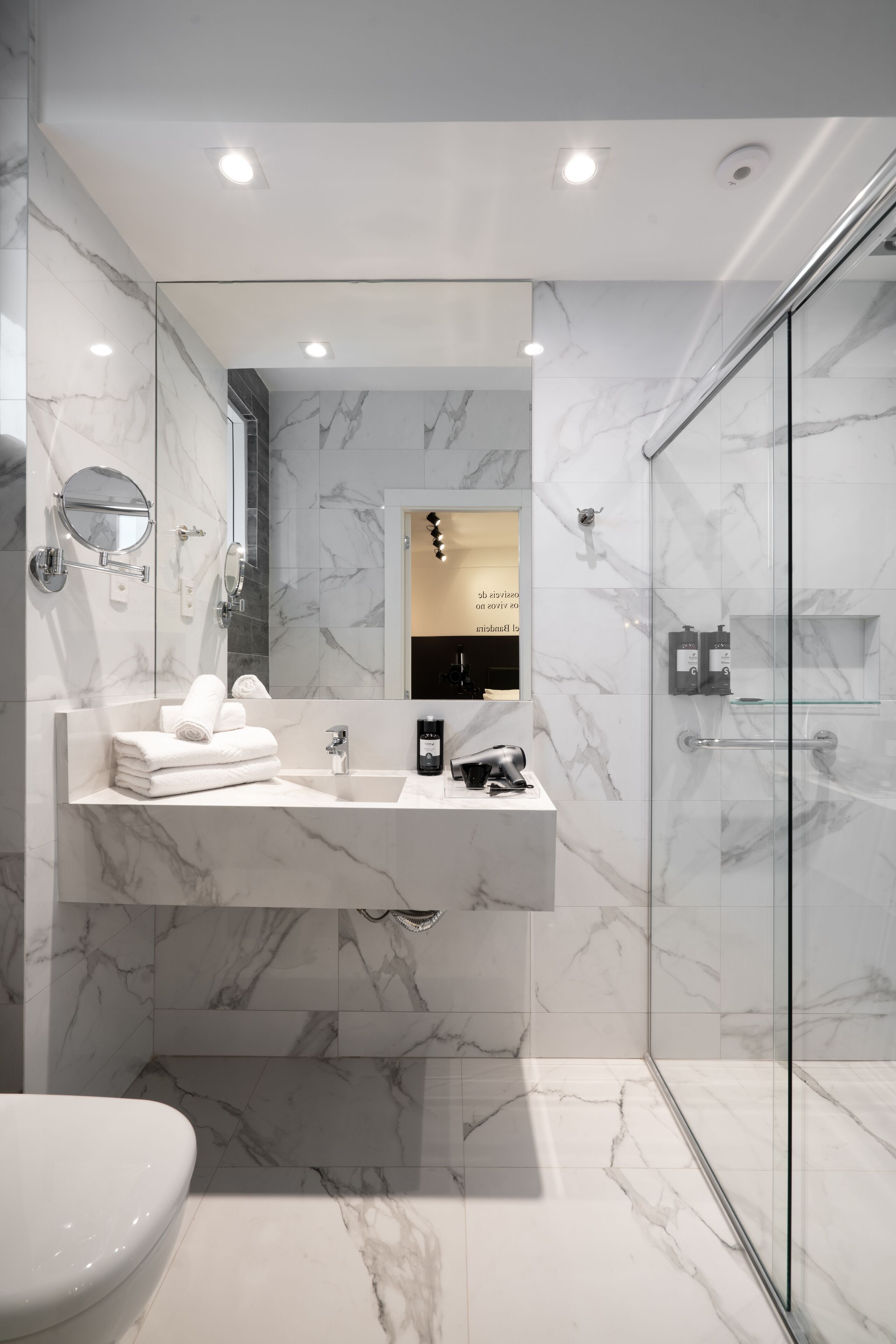 Un baño moderno con tocador de mármol, cabina de ducha de vidrio y un inodoro.