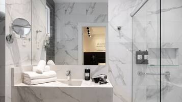 Un baño moderno con tocador de mármol, cabina de ducha de vidrio y un inodoro.