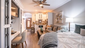 Une chambre moderne avec un grand lit, un bureau et, au fond, un coin cuisine.