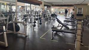 Une salle de sport équipée de divers appareils d’exercice, de miroirs et offrant un espace généreux.
