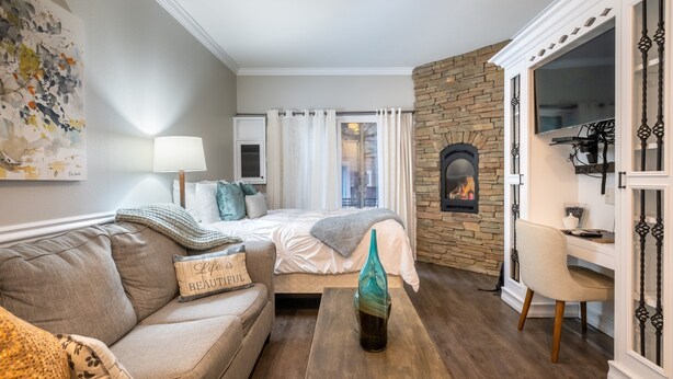 Une pièce confortable avec un lit, un canapé, une table basse et une cheminée.
