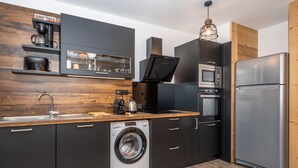 A modern kitchen with a built-in washing machine, a refrigerator, and a microwave.