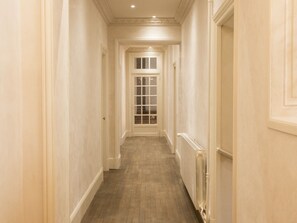 A narrow hallway with a wooden floor and white walls. - Large family Suite garden view (Barbeville)