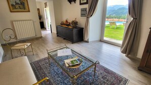 Amplia sala de estar con una mesa de centro de vidrio, un sofá y vistas a una piscina y montañas a través de un gran ventanal corredero.