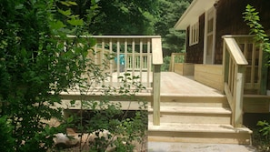 A wooden deck leading to a house with a porch.