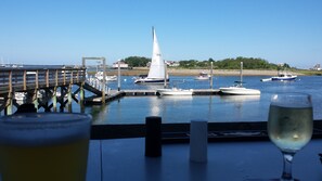 A waterfront view with a sailboat, docked boats, and a wooden pier.