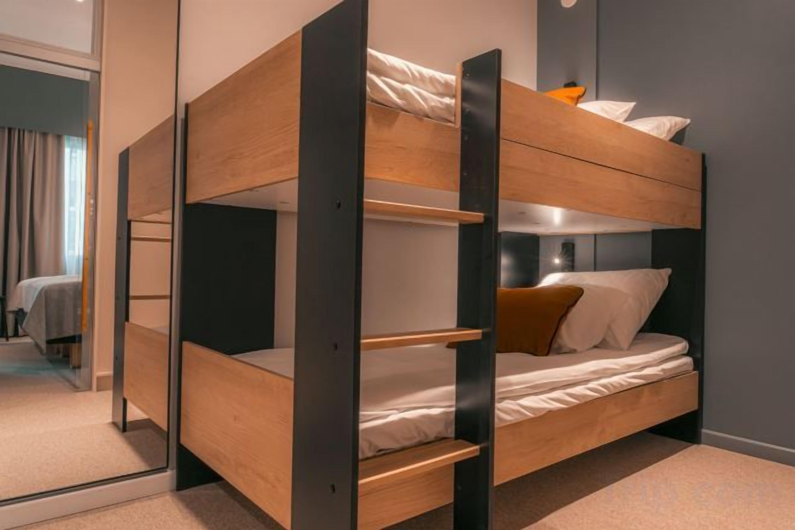 Un lit superposé avec une structure en bois et un matelas avec des oreillers.
