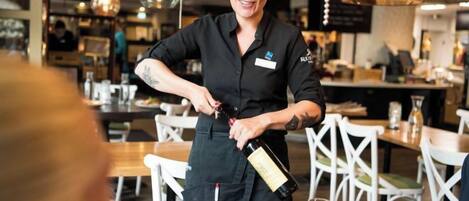 A person pouring a drink into a glass at a restaurant.