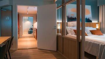 Une chambre d’hôtel avec un lit, une table de chevet et vue sur le couloir.
