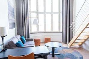 Een moderne woonkamer met een bank, een rond bijzettafeltje en een trap.