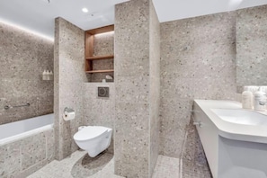 Une salle de bain moderne équipée d’une baignoire, de toilettes et d’un meuble-lavabo.