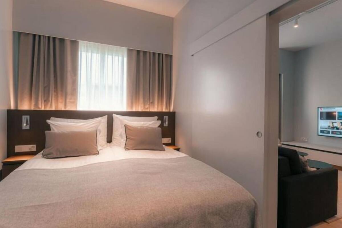 Une chambre d’hôtel moderne dotée d’un grand lit, d’un téléviseur à écran plat et d’un bureau avec une chaise.