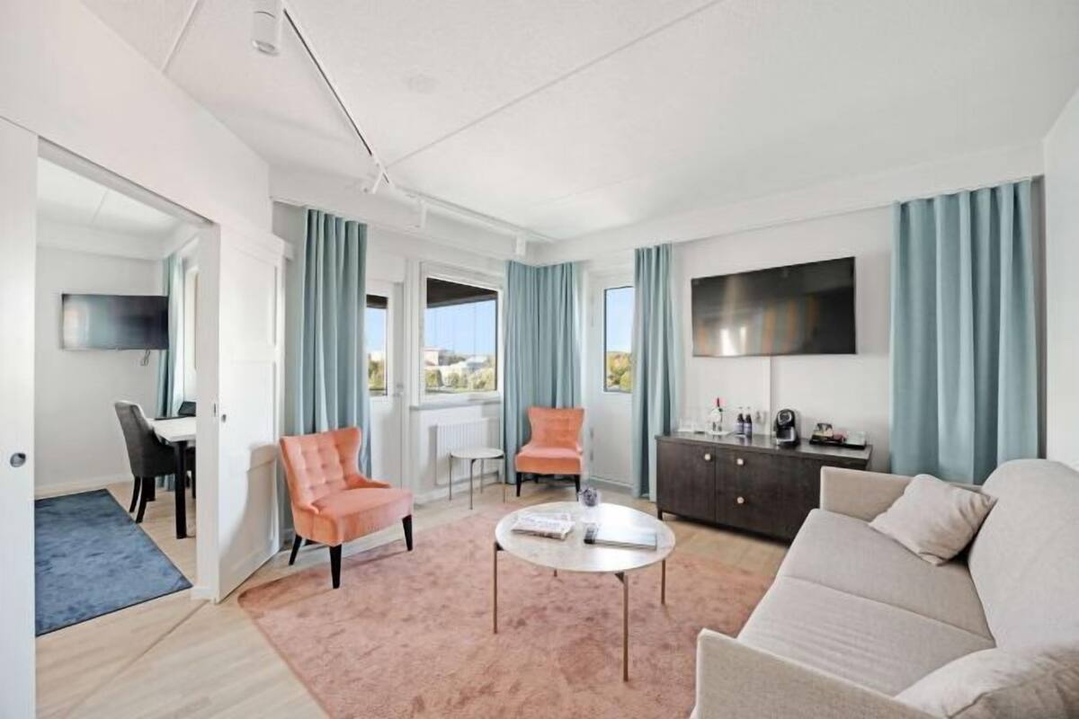 Un salon moderne comprenant un canapé, des fauteuils, une table basse, un téléviseur et un coin repas.