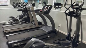 A gym with treadmills, elliptical machines, and a stationary bike. - Cooks Beach Getaway LLC (Panama City Beach)