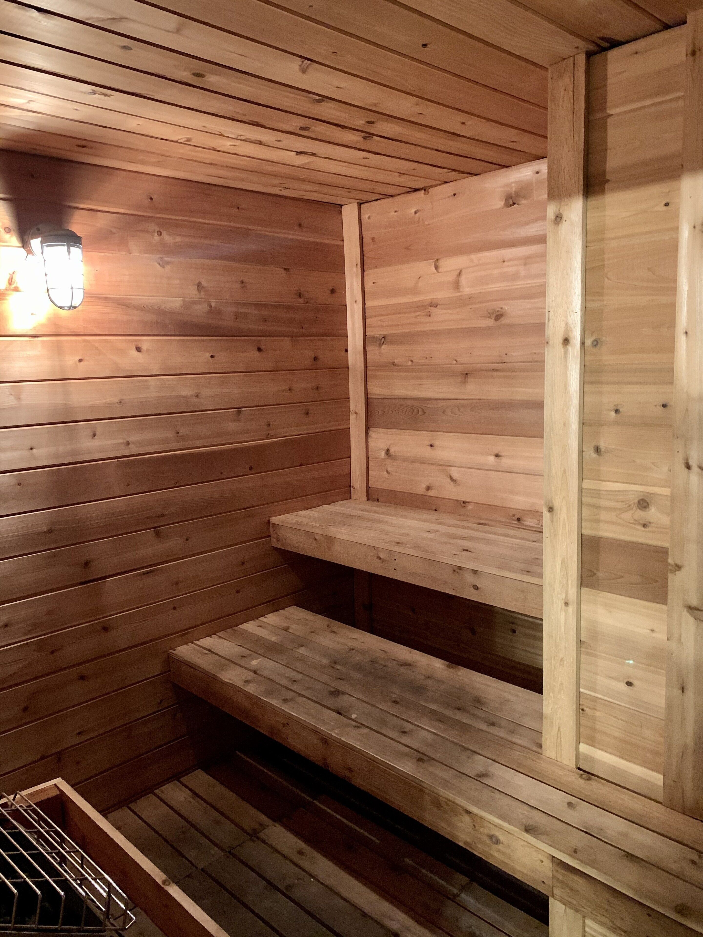 Una sauna in legno con panche e una seduta.