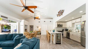 A spacious living area with a blue sofa, wooden dining table, and ceiling fans. - SOUTHERNMOST SWIM AND SOCIAL CLUB  (Key West)