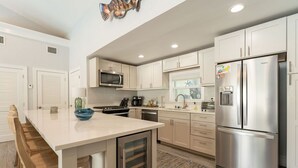 A modern kitchen with white cabinets, stainless steel appliances, and a central island. - SOUTHERNMOST SWIM AND SOCIAL CLUB  (Key West)